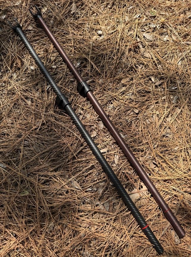 Two Minelab Manticore two-piece carbon-fiber lower shafts, in black and red/black, joined by a clamp-type cam lock